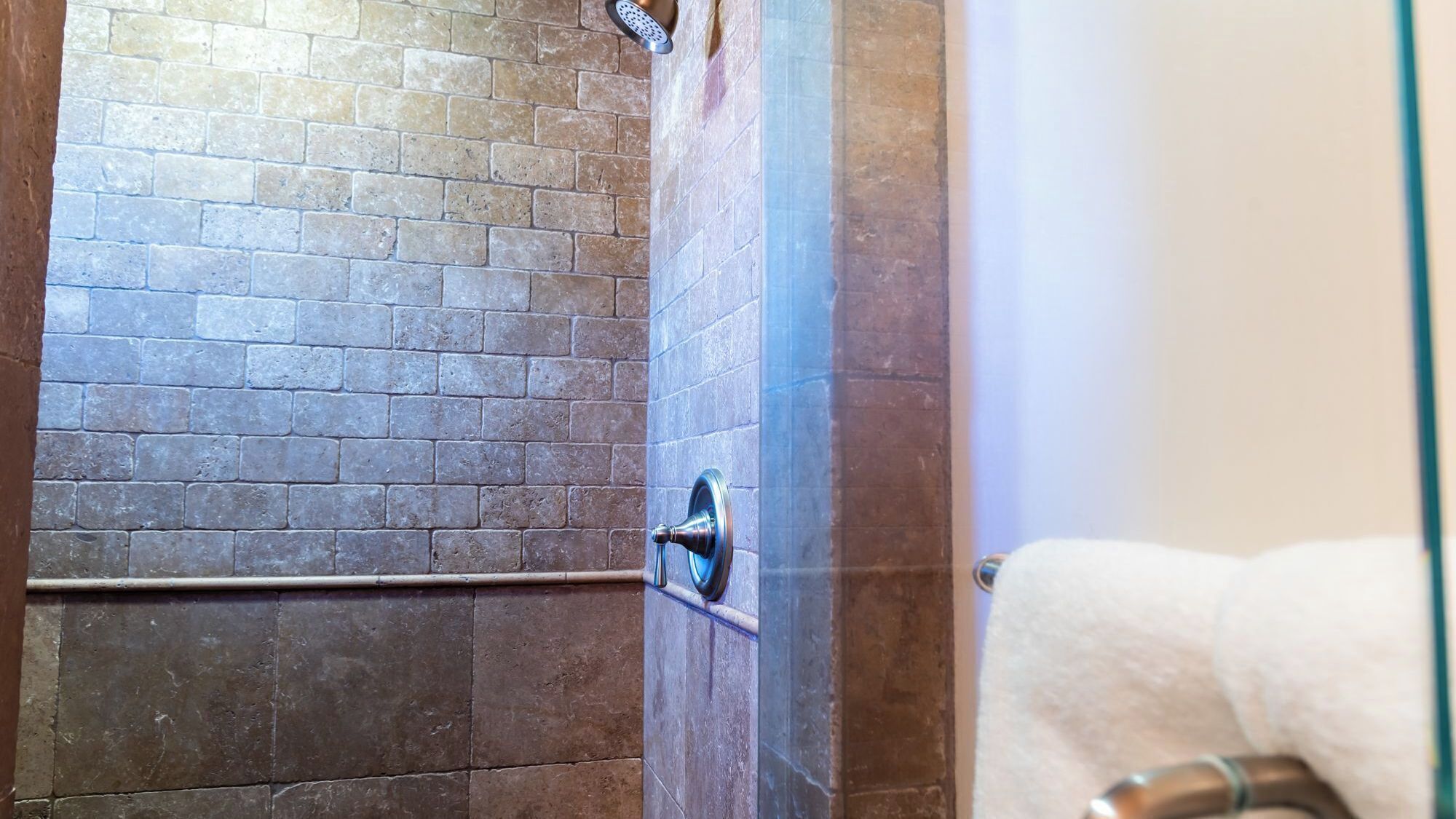 A bathroom with a tiled shower wall and a towel rack.