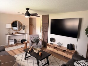 A modern living room with a flat-screen TV, a ceiling fan, a sofa, a coffee table, and a fireplace. - Modern 2-bedroom house in Beautiful Mount Vernon, Ohio (Mount Vernon)