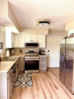 A modern kitchen with white cabinets, stainless steel appliances, and a patterned rug. - Modern 2-bedroom house in Beautiful Mount Vernon, Ohio (Mount Vernon)