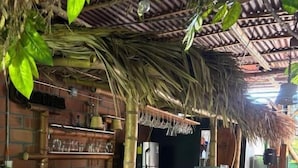 A bar area with a thatched roof, bamboo stools, and a bar counter. - casa raizal (Envigado)