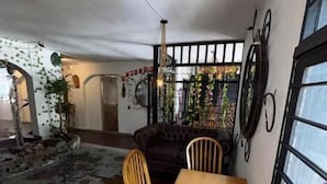 A dining area with a wooden table and chairs, a black sofa, and a window with a view of the street. - casa raizal (Envigado)