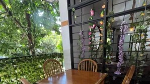 A wooden table and chairs set up on a balcony with a view of greenery and a black metal fence. - casa raizal (Envigado)