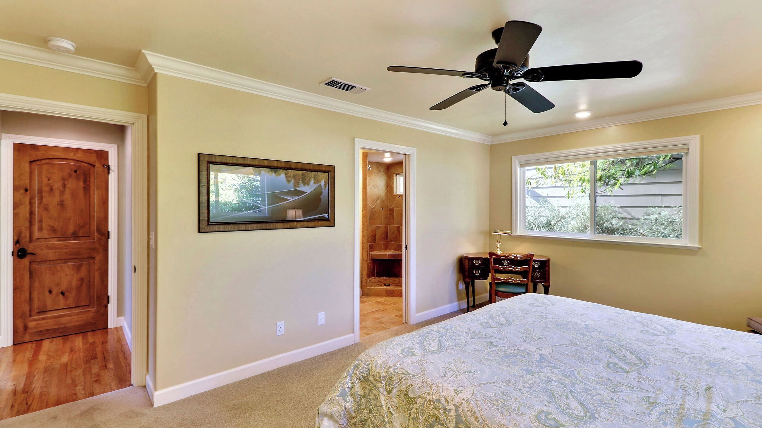 Un dormitorio con cama, ventilador de techo, ventana y puerta.