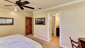 A bedroom with a bed, a ceiling fan, a wooden door, and a hallway leading to a bathroom. - Two Sweet by Avantstay Walk to Downtown + Private Patio Historic Paso Robles Wine Country (Paso Robles)