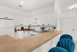 A modern kitchen with white cabinets, a central island, and a microwave. - Secret Lake Resort Balcony Retreat (Kissimmee)
