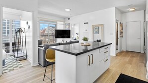 Une cuisine moderne dotée d’un îlot central, d’un téléviseur à écran plat et offrant une vue sur la ville.