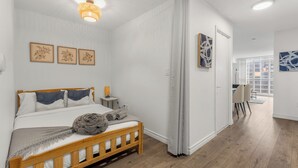 Un dormitorio con cama de madera, paredes blancas y una lámpara en el techo.