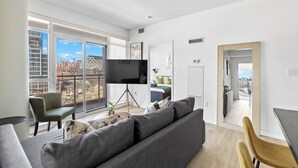 Un salon moderne avec un grand canapé, un téléviseur et un coin repas.