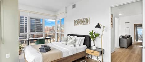 Un dormitorio moderno con una cama grande, un escritorio y vistas a la ciudad.
