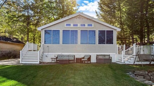 A single-story house with a front porch, a small deck, and a well-maintained lawn. - Breakaway Lake House (Northwood)