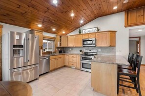 Eine Küche mit Holzschränken, Edelstahlgeräten und einer Arbeitsplatte aus Granit.