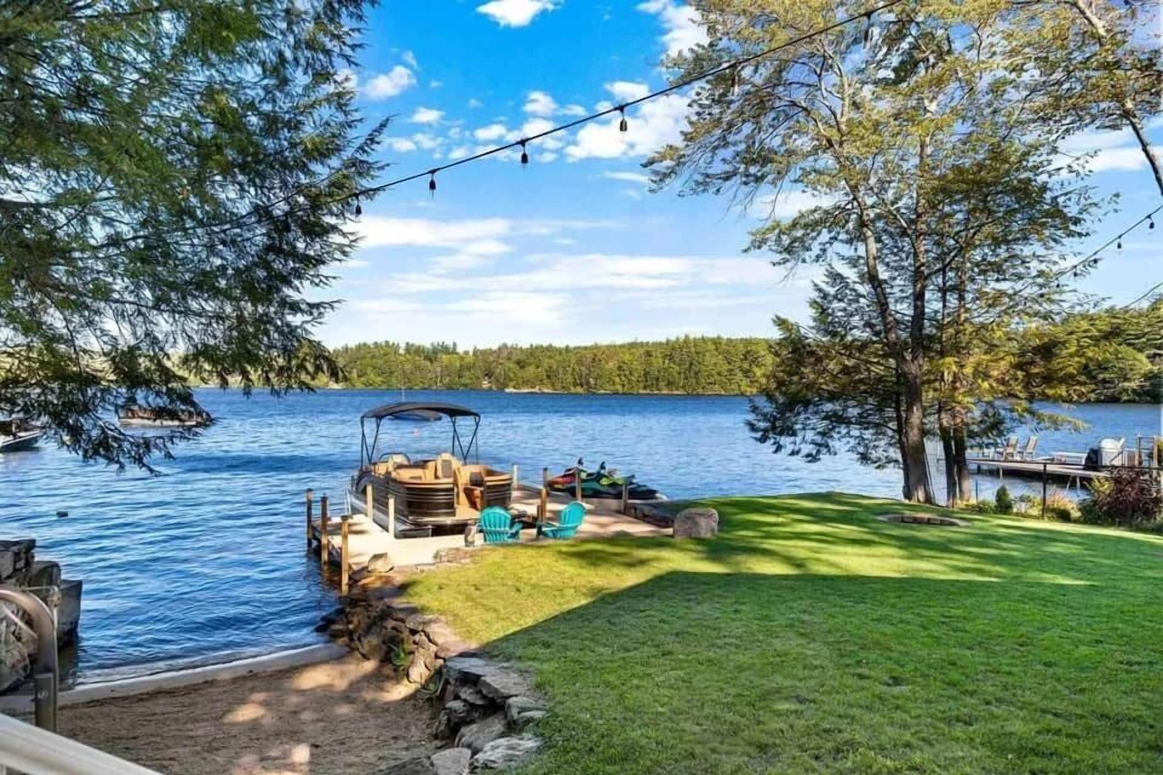 Une terrasse au bord du lac, aménagée avec du mobilier d’extérieur, une jetée et un bateau.