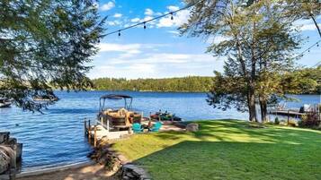 Une terrasse au bord du lac, aménagée avec du mobilier d’extérieur, une jetée et un bateau.