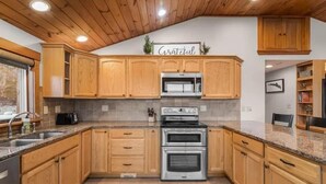 A kitchen with wooden cabinets, a stainless steel oven, and a granite countertop. - Breakaway Lake House (Northwood)