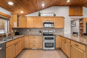 A kitchen with wooden cabinets, a stainless steel oven, and a granite countertop.