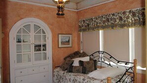 Una camera da letto con un letto, una cassettiera, una finestra con tende e una ventola a soffitto.