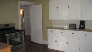 Una cucina con mobili bianchi, un fornello e un tostapane.