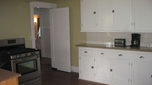 A kitchen with white cabinets, a stove, and a toaster. - Jany House by Avantstay Historic Craftsman + Garden Patio Walk to Downtown Paso (Paso Robles)