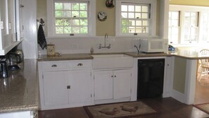 A kitchen with white cabinets, a microwave, a dishwasher, and a window with a view of greenery. - Jany House by Avantstay Historic Craftsman + Garden Patio Walk to Downtown Paso (Paso Robles)
