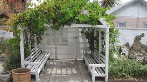 A white pergola with a bench under it, surrounded by greenery and a white fence. - Jany House by Avantstay Historic Craftsman + Garden Patio Walk to Downtown Paso (Paso Robles)
