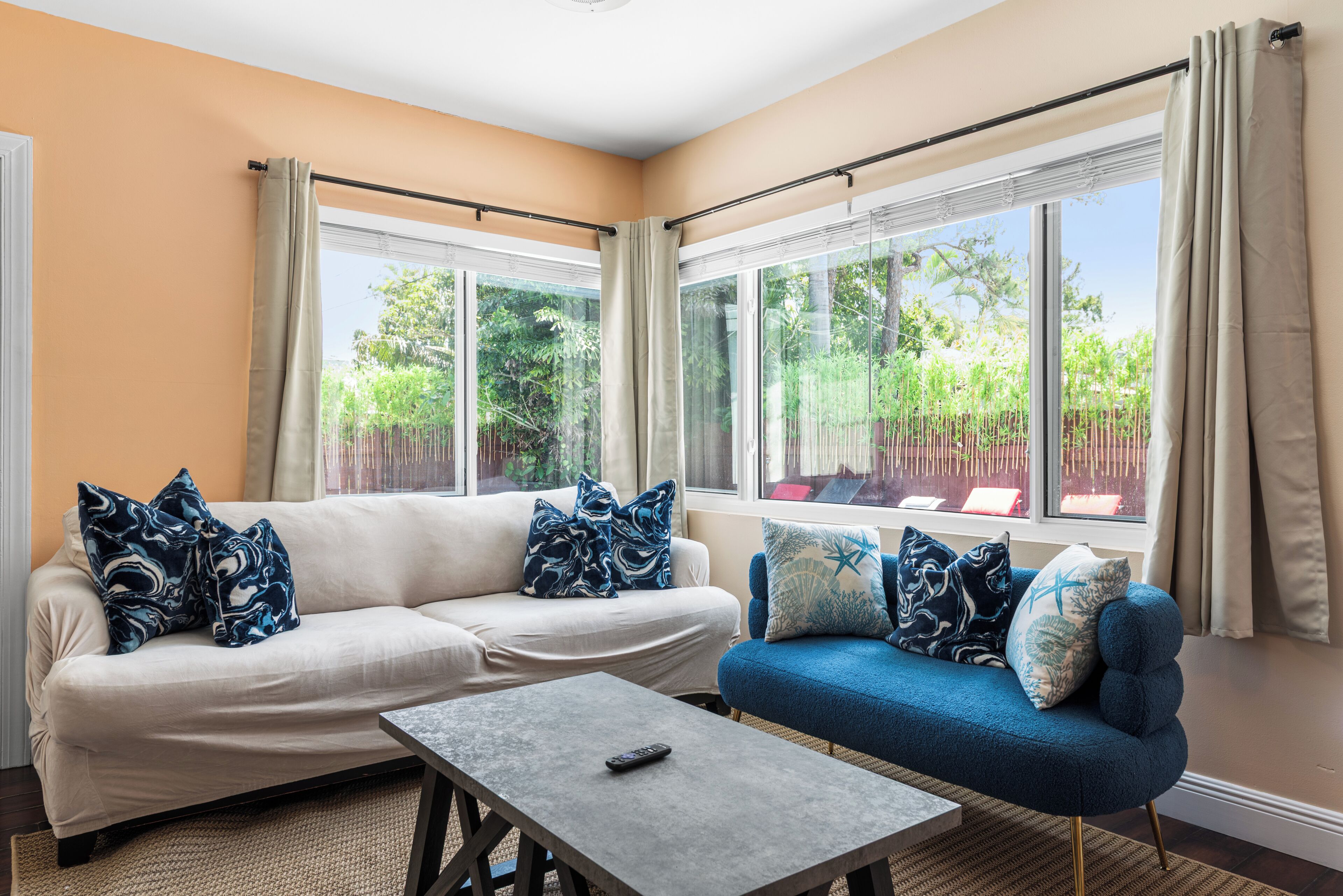 A living room with a beige sofa, a blue sofa, and a coffee table.