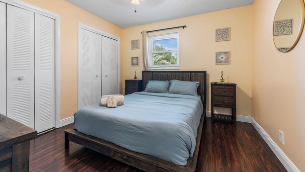 A bedroom with a bed, a nightstand, a dresser, a ceiling fan, and a window.