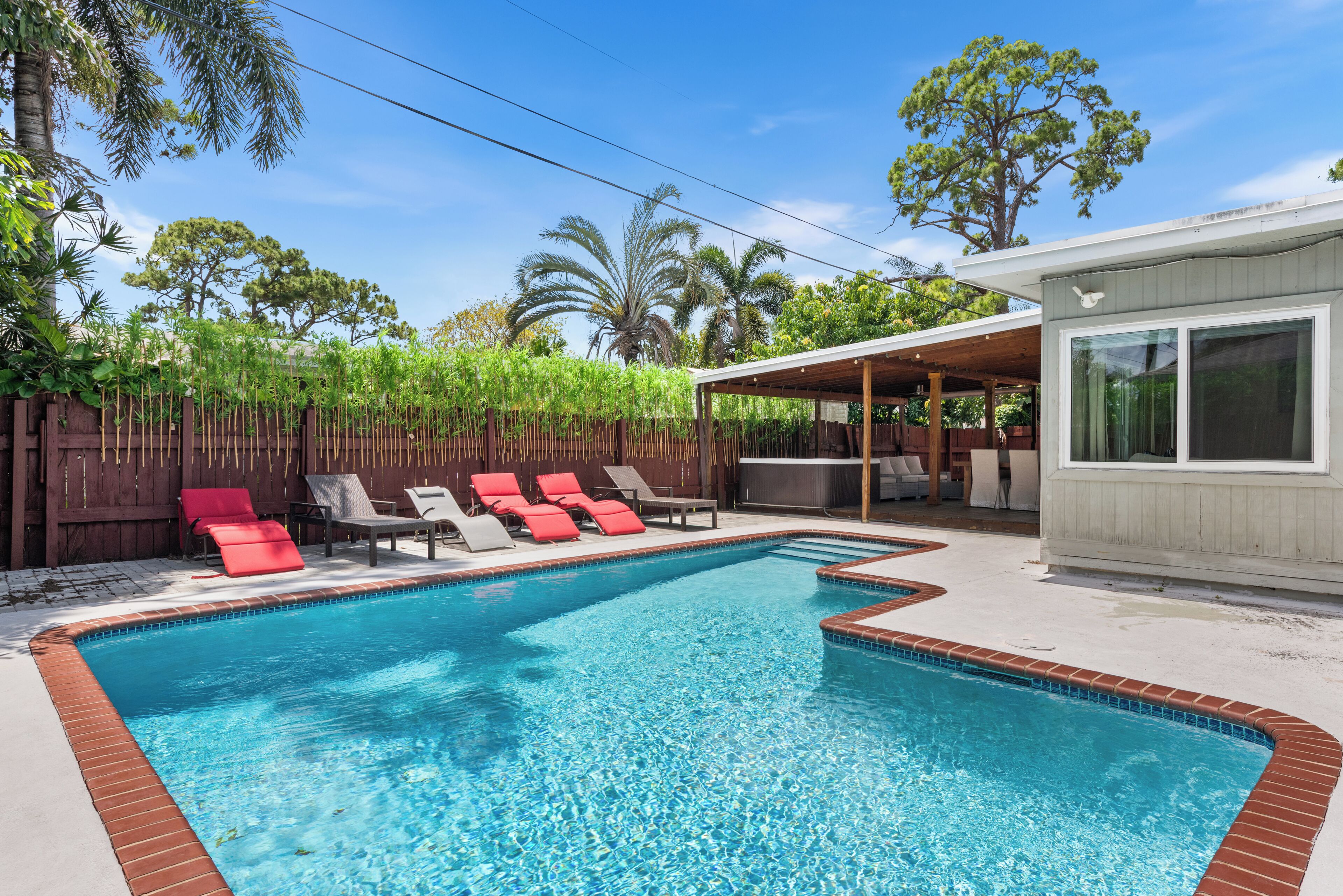 Une piscine rectangulaire dont le bord est recouvert de carrelage, entourée d’une terrasse en bois.