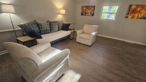 A living room with a sofa, two armchairs, a coffee table, and two lamps. - Open floor-plan - Large Covered Patio - Kitchen Island - 5 beds (Dothan)