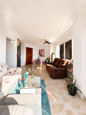 Ein Wohnzimmer mit Sofa, Couchtisch und Essbereich mit Stühlen und Tisch.