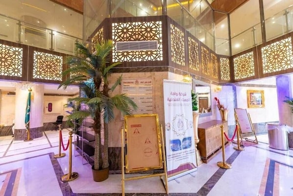 A lobby with a decorative partition, a reception desk, and a potted plant. - Safeer Almisk Hotel Mecca (Makkah)