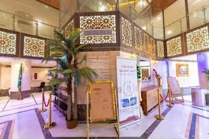 Un vestíbulo con un separador decorativo, una recepción y una planta en maceta.