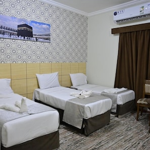 Habitación de hotel con dos camas, un papel tapiz decorativo, un equipo de aire acondicionado y vista a una mezquita.