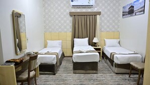 A hotel room with two beds, a desk, a chair, a lamp, and a wall-mounted air conditioner. - Safeer Almisk Hotel Mecca (Makkah)