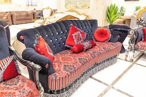 A luxurious sofa with tufted upholstery and decorative pillows, set in a well-appointed room with classic furniture and a tiled floor. - Safeer Almisk Hotel Mecca (Makkah)