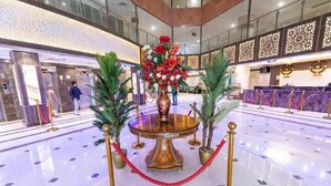 A lobby with a marble floor, a central round table with a floral arrangement, and a reception desk. - Safeer Almisk Hotel Mecca (Makkah)