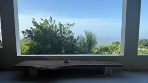 A room with a large window offering a view of trees and hills.
