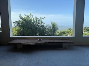 A room with a large window offering a view of trees and hills.