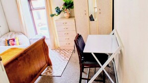 A bedroom with a bed, a desk, a chair, a dresser, a mirror, and a plant. - Cosy 3-bedroom Townhouse With Garden (Wexford)