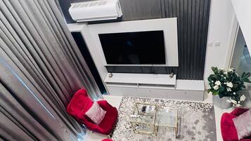 Un salon moderne avec un canapé rouge, une table basse et un téléviseur à écran plat fixé à un mur gris.