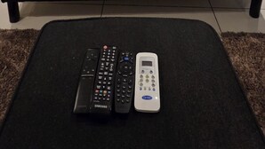 Moderni makuuhuone, jossa on suuri sänky, musta sohva ja seinälle asennettu taideteos.