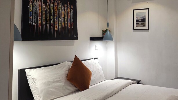 A modern bedroom with a large bed, a wall-mounted air conditioner, and a ceiling light. - EBS PROPERTIES (Accra)