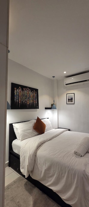 Ein modernes Schlafzimmer mit einem großen Bett, einer Wand-Klimaanlage und einer Deckenleuchte.