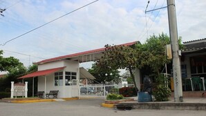 Un edificio con acceso cubierto, un área cercada y un banco.