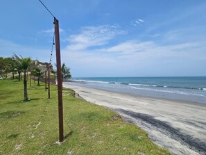 Ein Strand mit blauem Himmel, einer Rasenfläche und einer Holzkonstruktion.