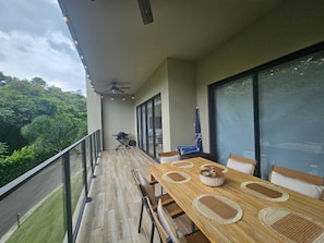 Ein Balkon mit Esstisch, Stühlen und Deckenventilator.