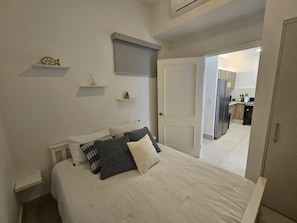 A bedroom with a bed, bedside tables, a wardrobe, and a door leading to a kitchen. - Beachfront Apartment, Family-Friendly Atmosphere, Just a Few Steps from the Ocean. (San Carlos)