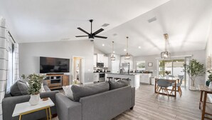 A modern living room with a grey sofa, a coffee table, and a TV. - Near WEC, Pet Friendly, King Beds & Spacious House (Ocala)