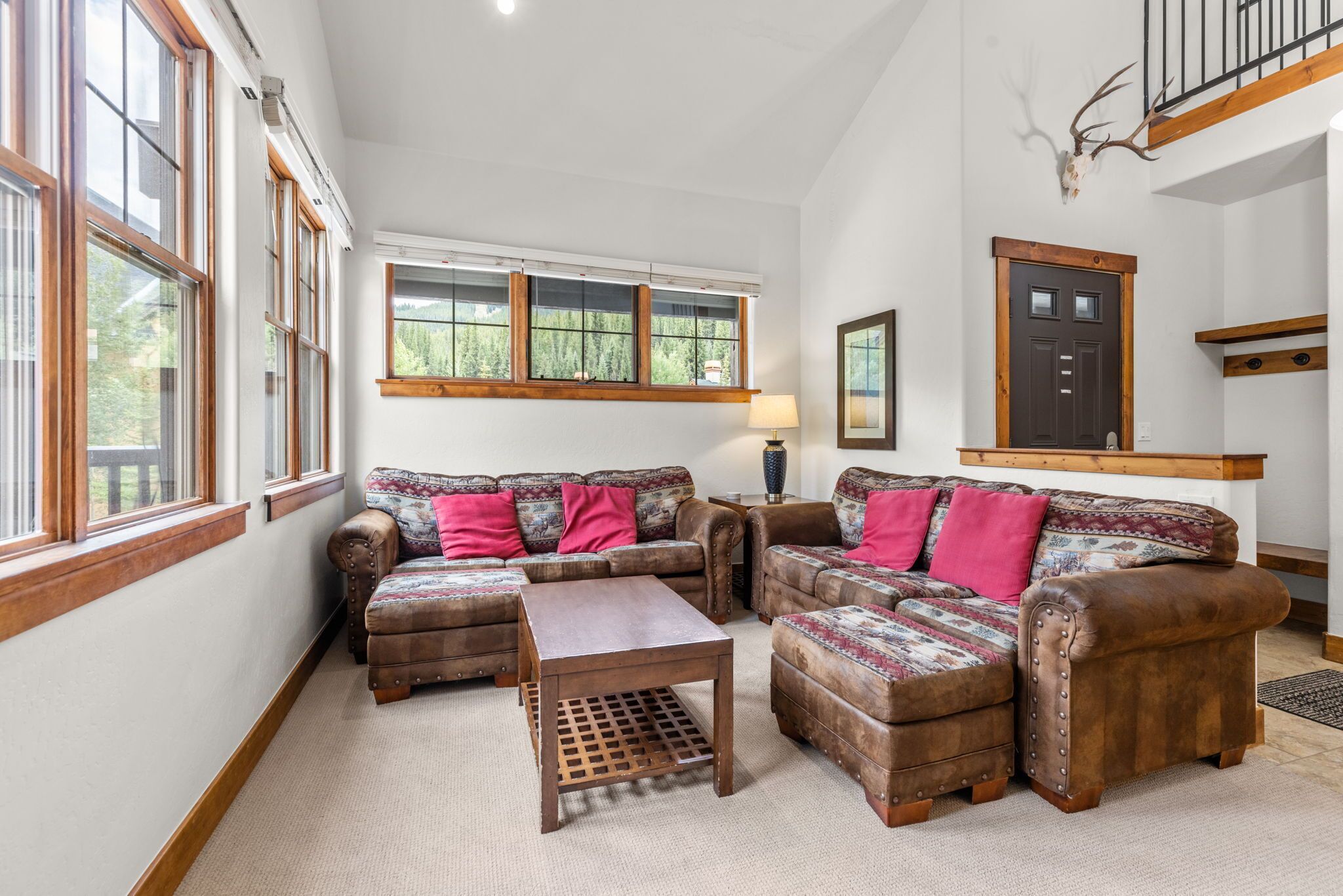 A cozy living room with a sofa set, ottomans, and a coffee table.