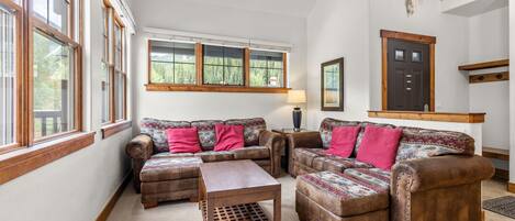A cozy living room with a sofa set, ottomans, and a coffee table.
