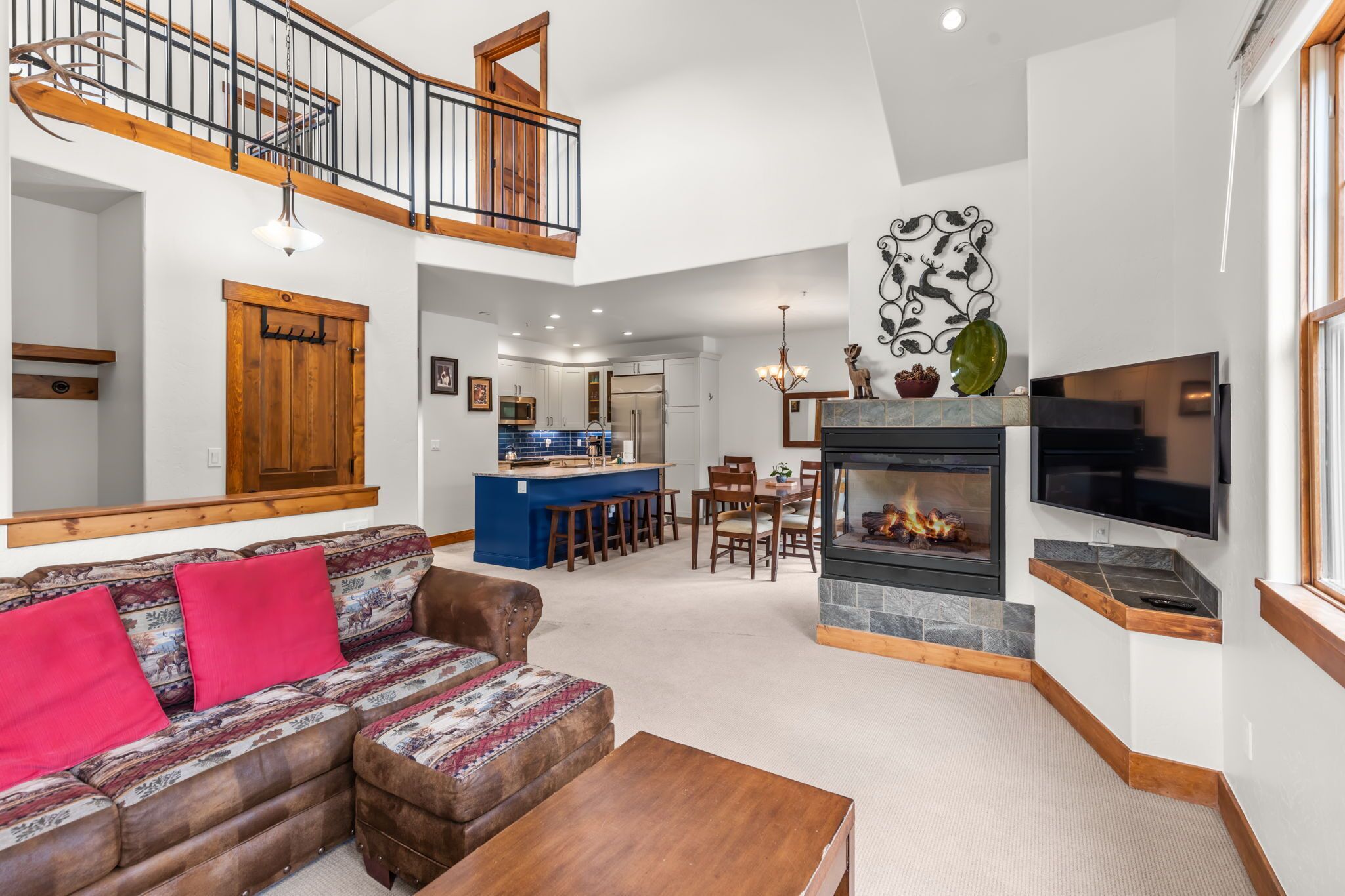 A spacious living area with a sofa, a fireplace, a dining table, and a kitchen in the background.
